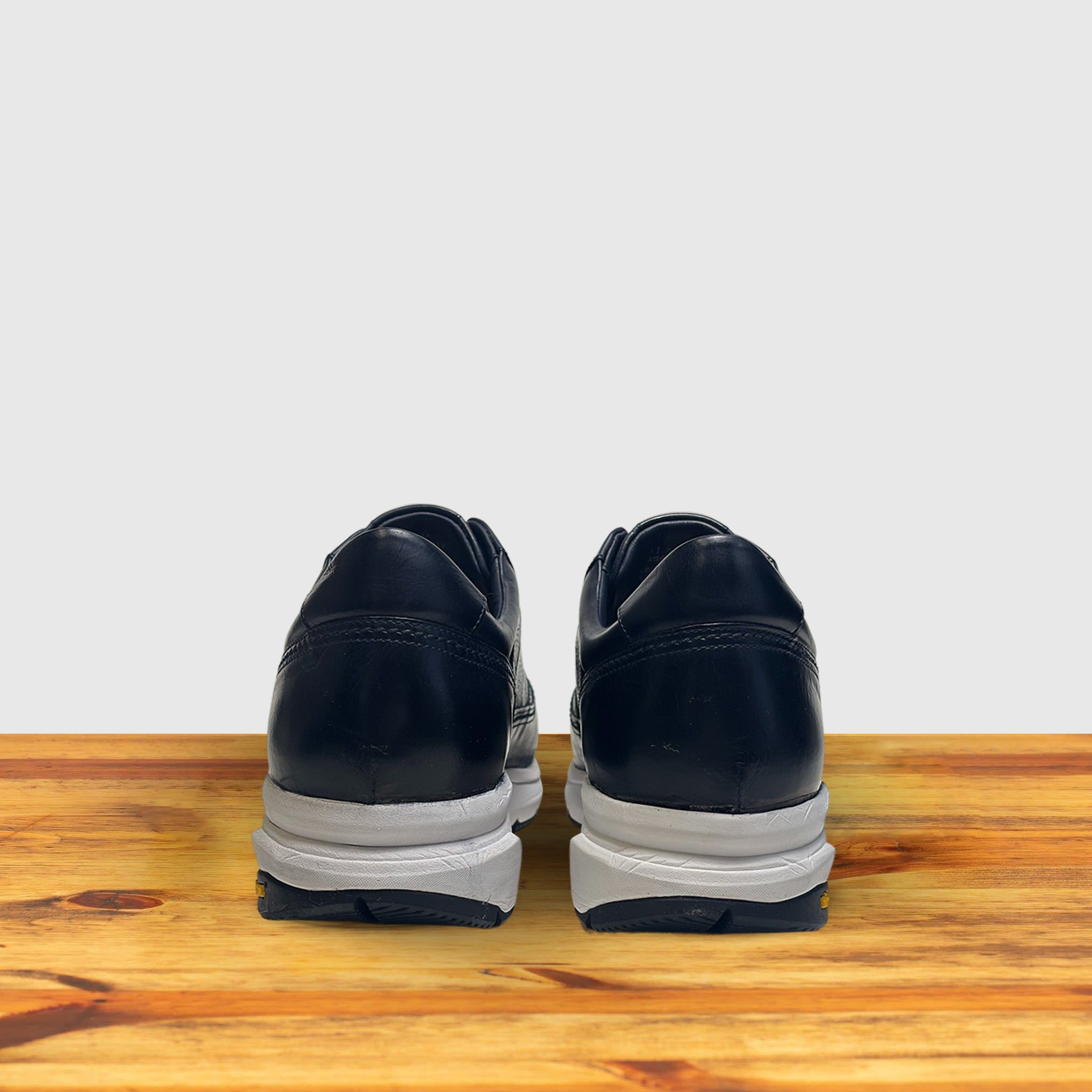 A pair of Blue sneaker with a white sole on a wooden surface