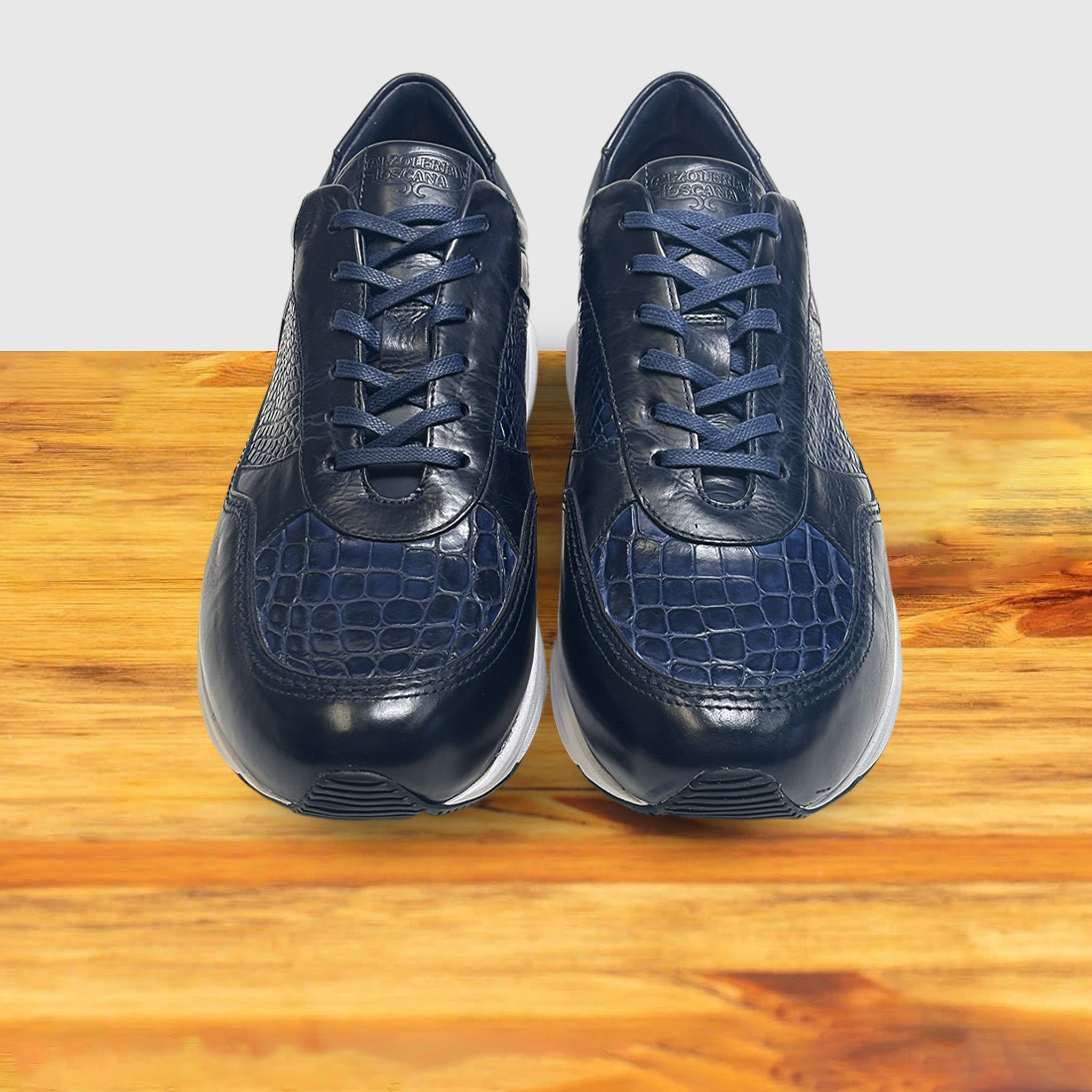 Pair of Blue sneaker with a white sole on a wooden surface