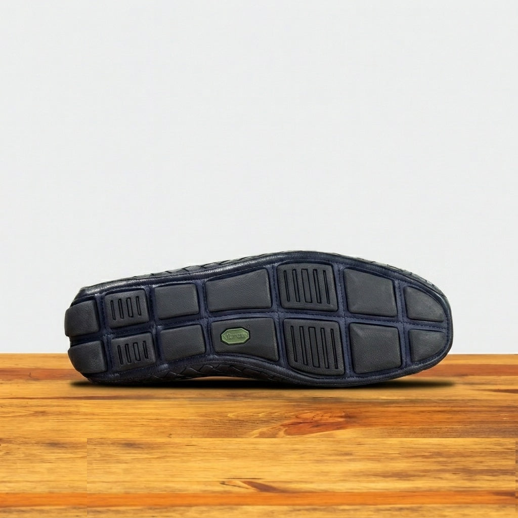 Outsole of a Navy Blue loafer shoe on a wooden surface