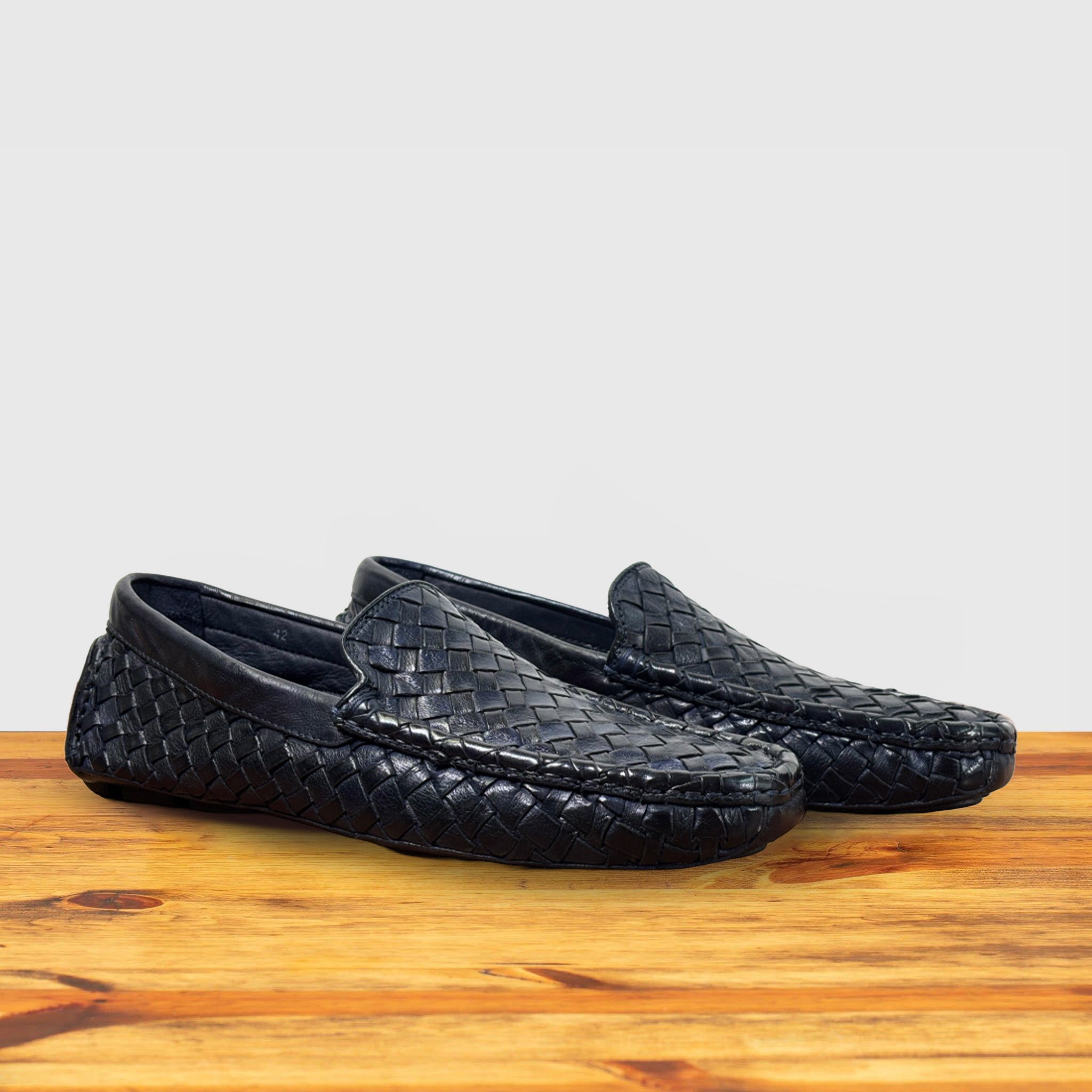 Pair of Navy Blue loafer shoe with woven pattern on a wooden surface