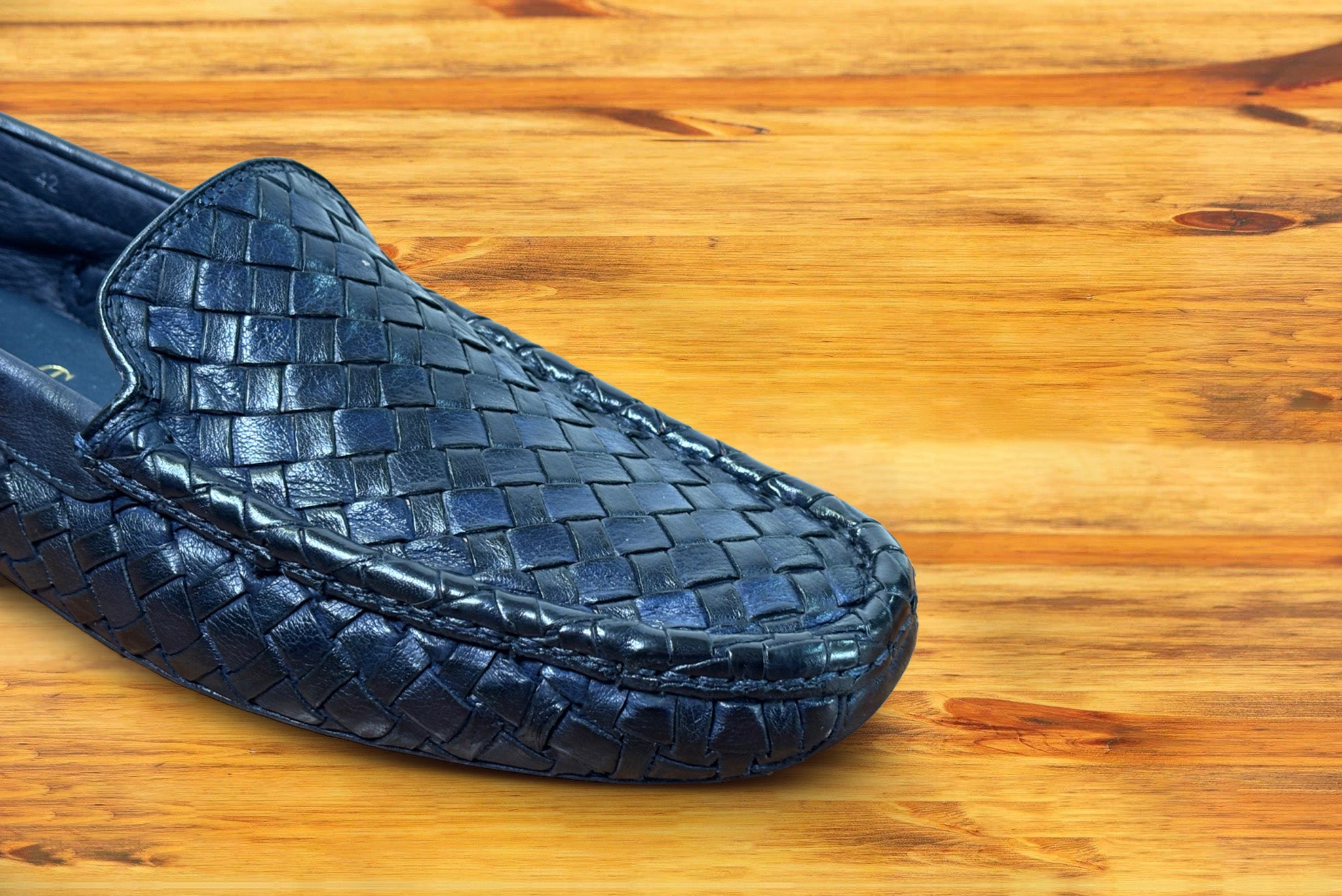 Navy Blue loafer shoe with woven pattern on a wooden surface