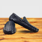 Pair of navy blue woven leather slip-on loafers, one upright and one angled, on a wooden surface