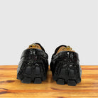 A pair of burgundy Genuine Crocodile loafers with block soles , shown from the back on a wooden surface against a light gray background.