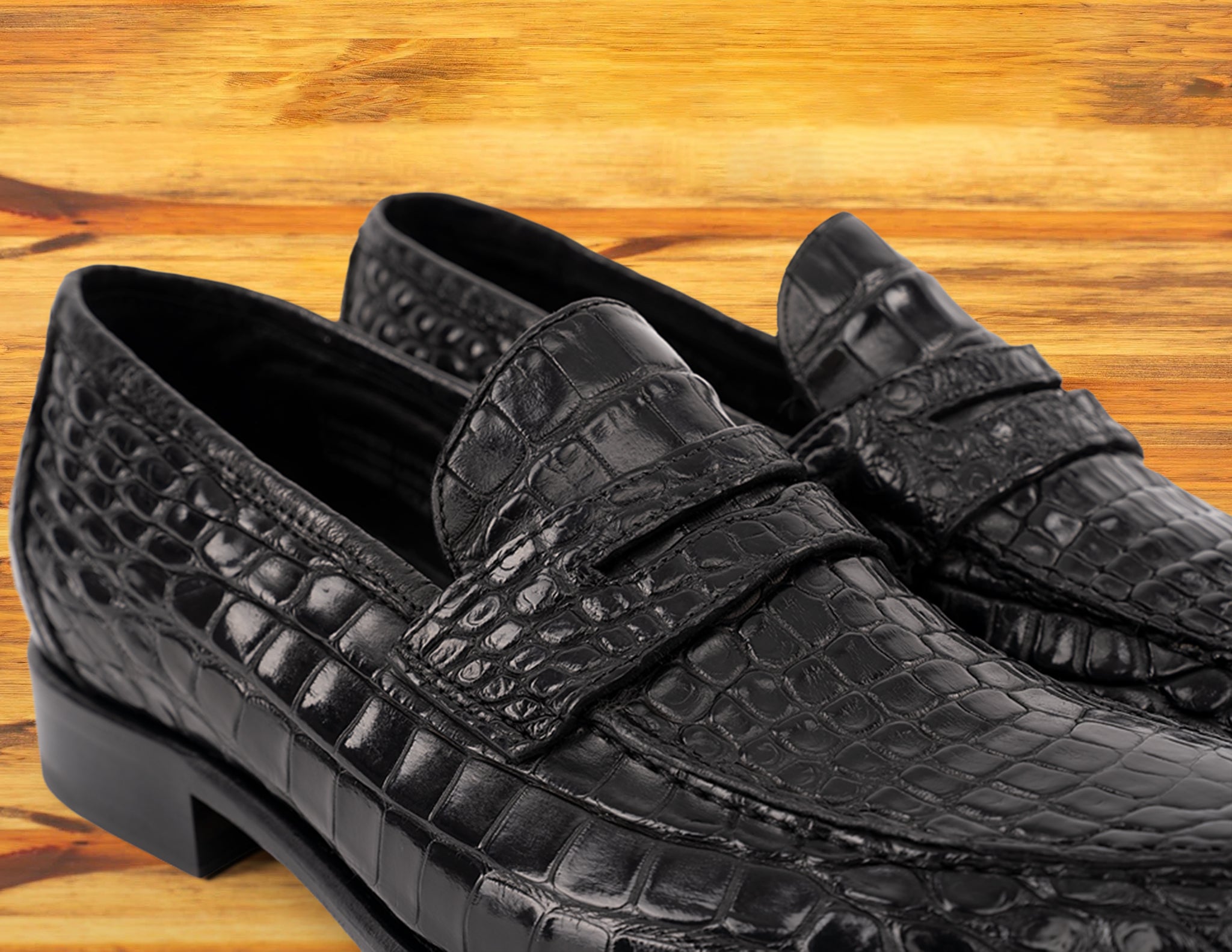 Black leather loafer on a wooden surface