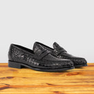 A Pair of Black leather loafer on a wooden surface with a light gray background