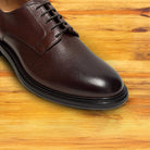 Close up of a Tobacco leather dress shoe on a wooden surface