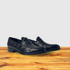 A pair of crocodile loafer shoe on a wooden surface with a light gray background