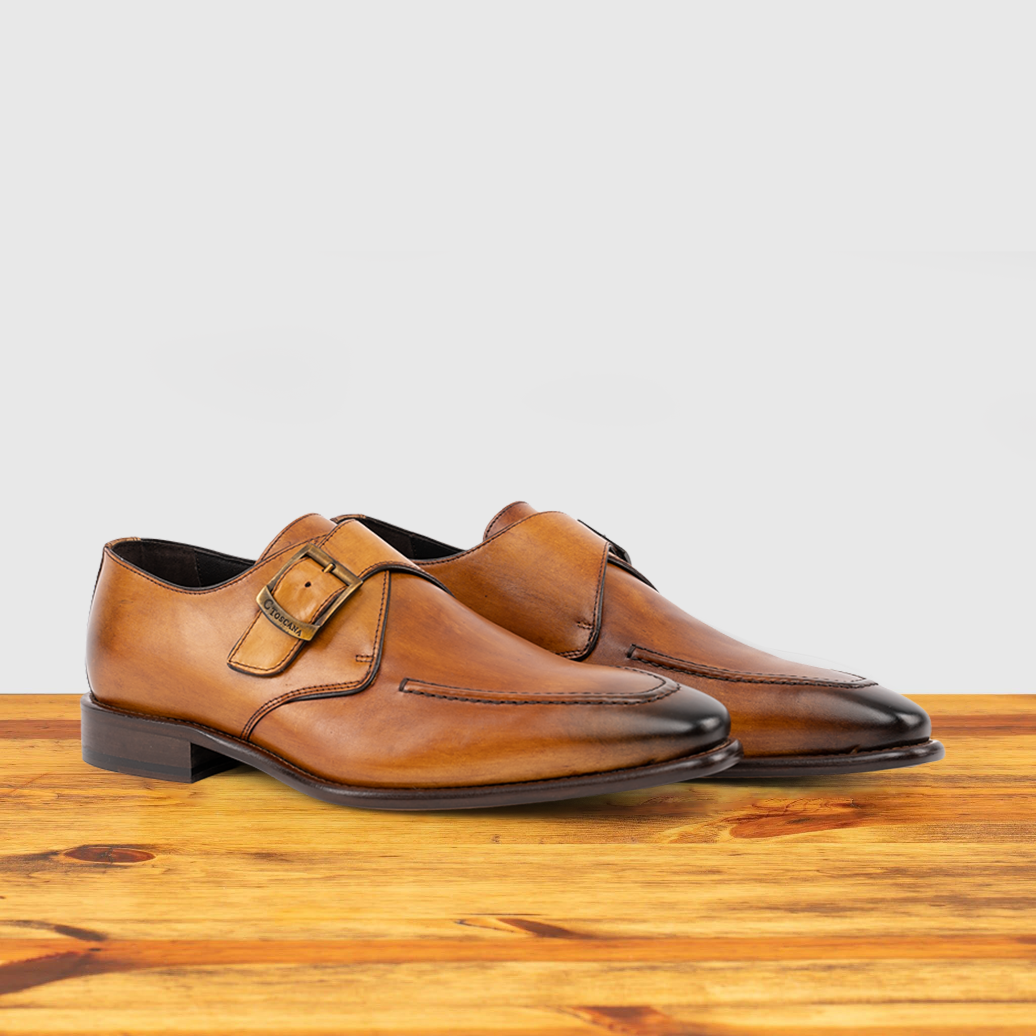 Pair of Caramel leather dress shoe with a buckle on a wooden surface