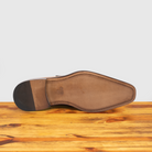 Outsole of Caramel leather dress shoe with a buckle on a wooden surface