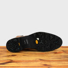 Outsole of brick leather ankle boot with a double zipper design on the side, placed on a wooden surface.