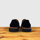 A pair of Black Venetian loafer with a rubber sole positioned on a wooden surface.