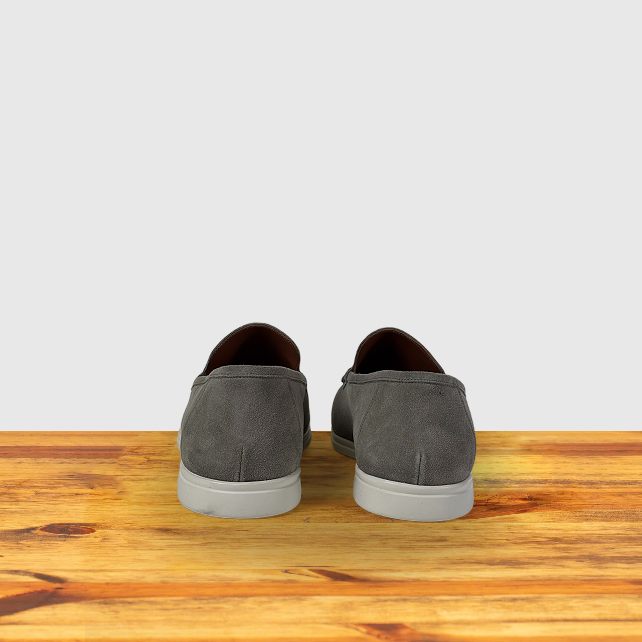 Gray loafer shoes on a wooden surface with a light gray background