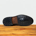 Close-up of a Dark Brown leather shoe sole on a wooden surface.