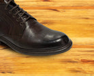 Close view of Dark Brown leather dress shoe on a wooden surface