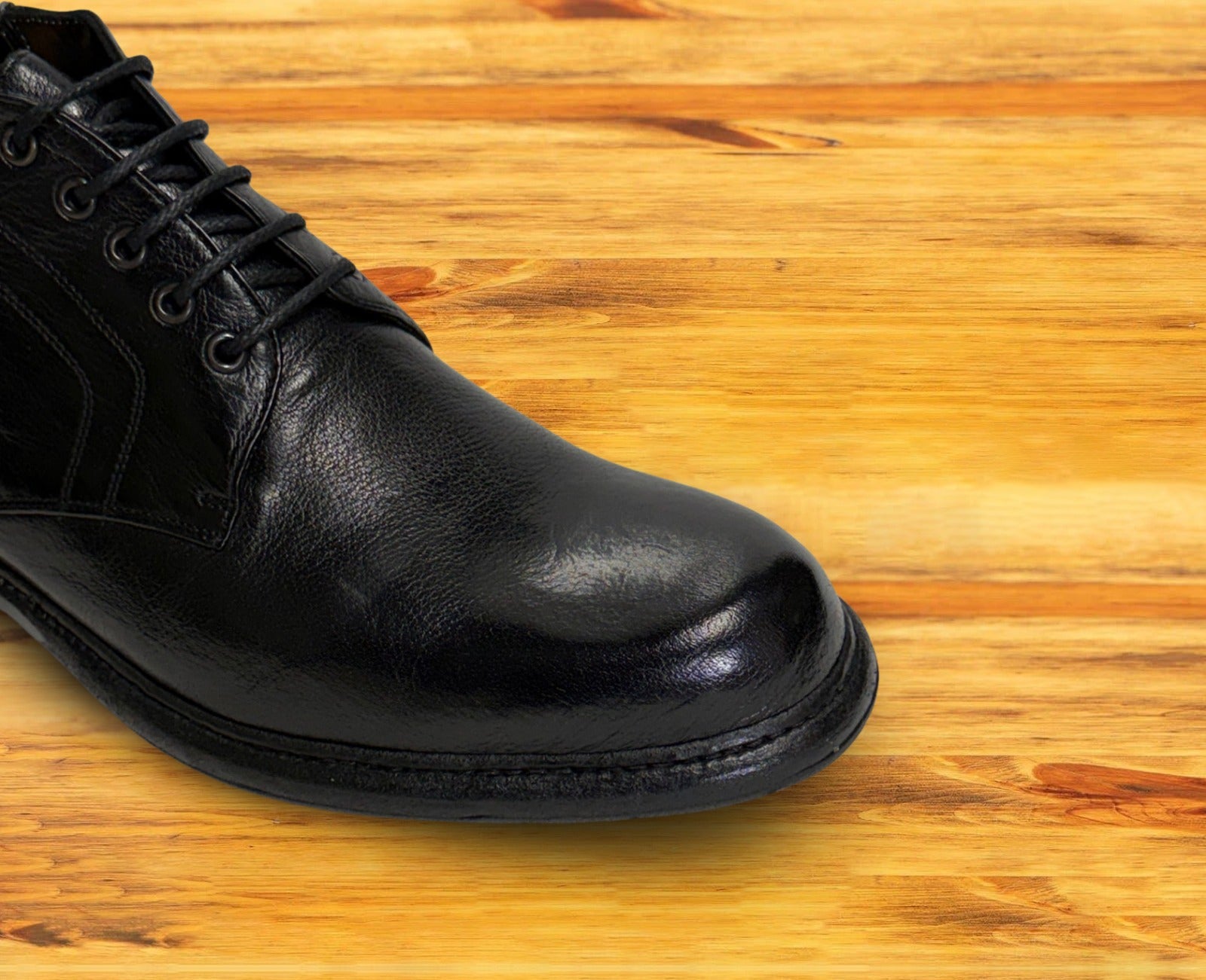 Black leather boot on a wooden surface