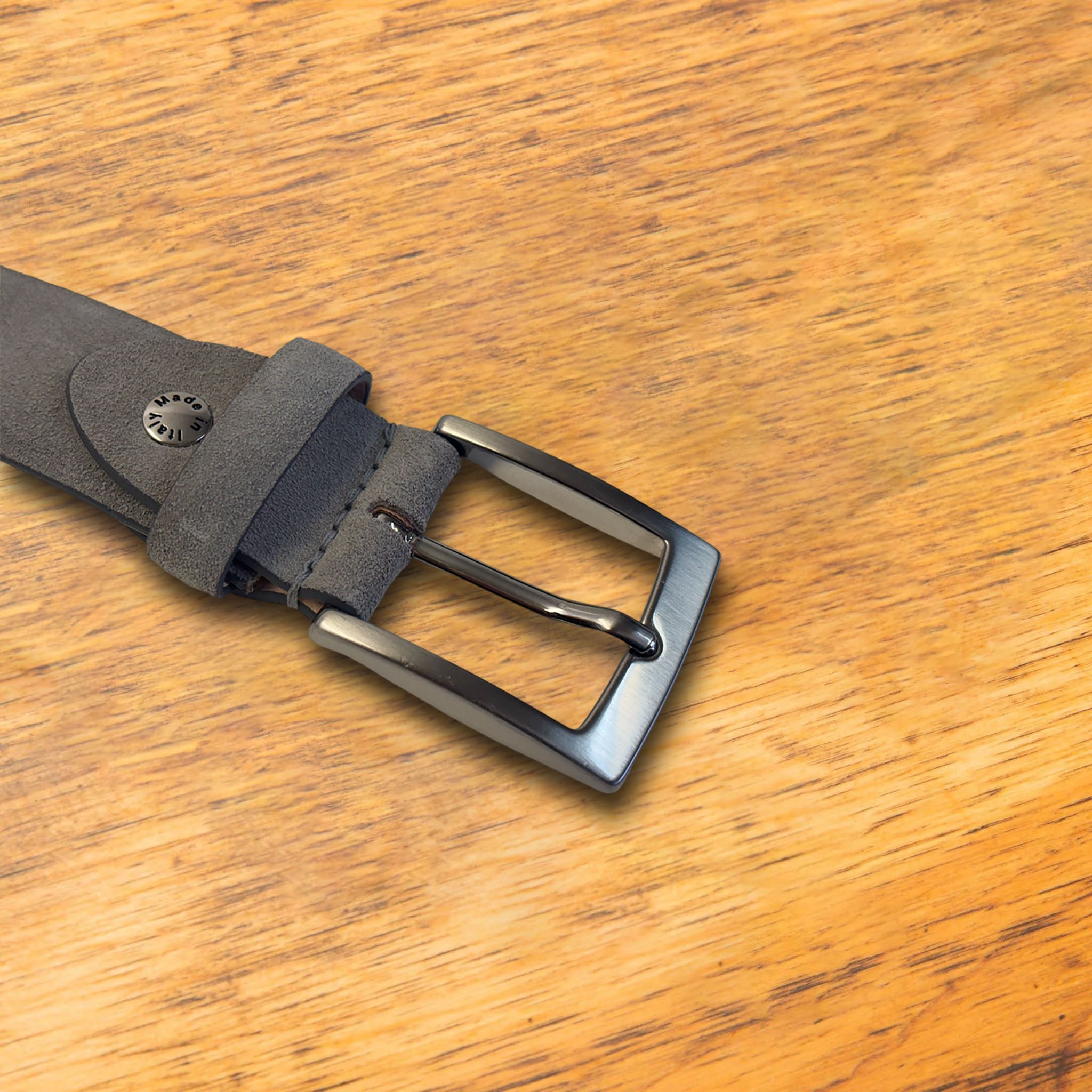Gray belt with a silver buckle on a wooden surface