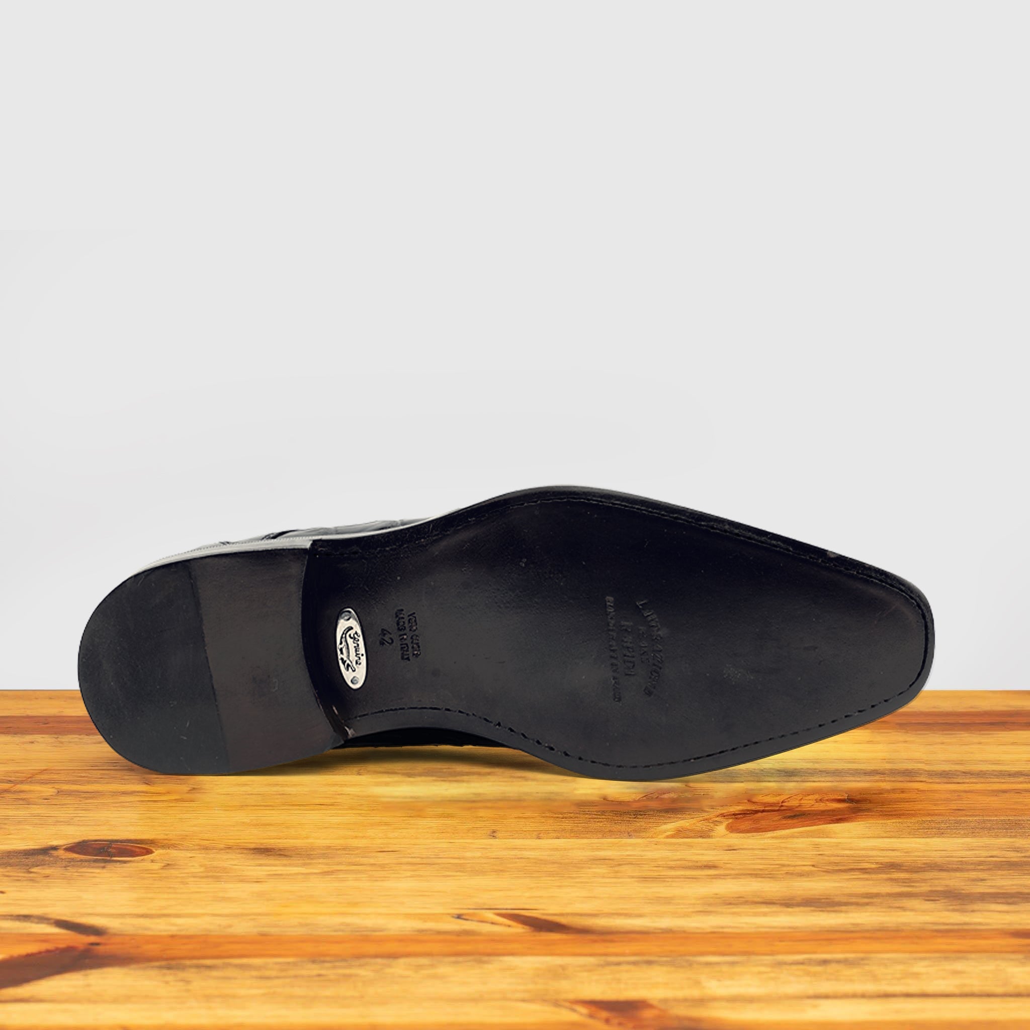 Outsole of Blue crocodile shoe on a wooden surface with a light gray background