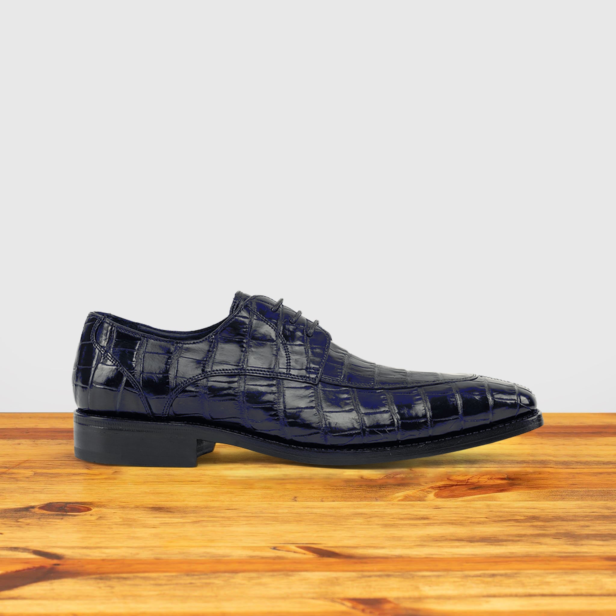 Blue crocodile shoe on a wooden surface with a light gray background