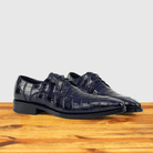 A pair of Blue crocodile shoe on a wooden surface with a light gray background