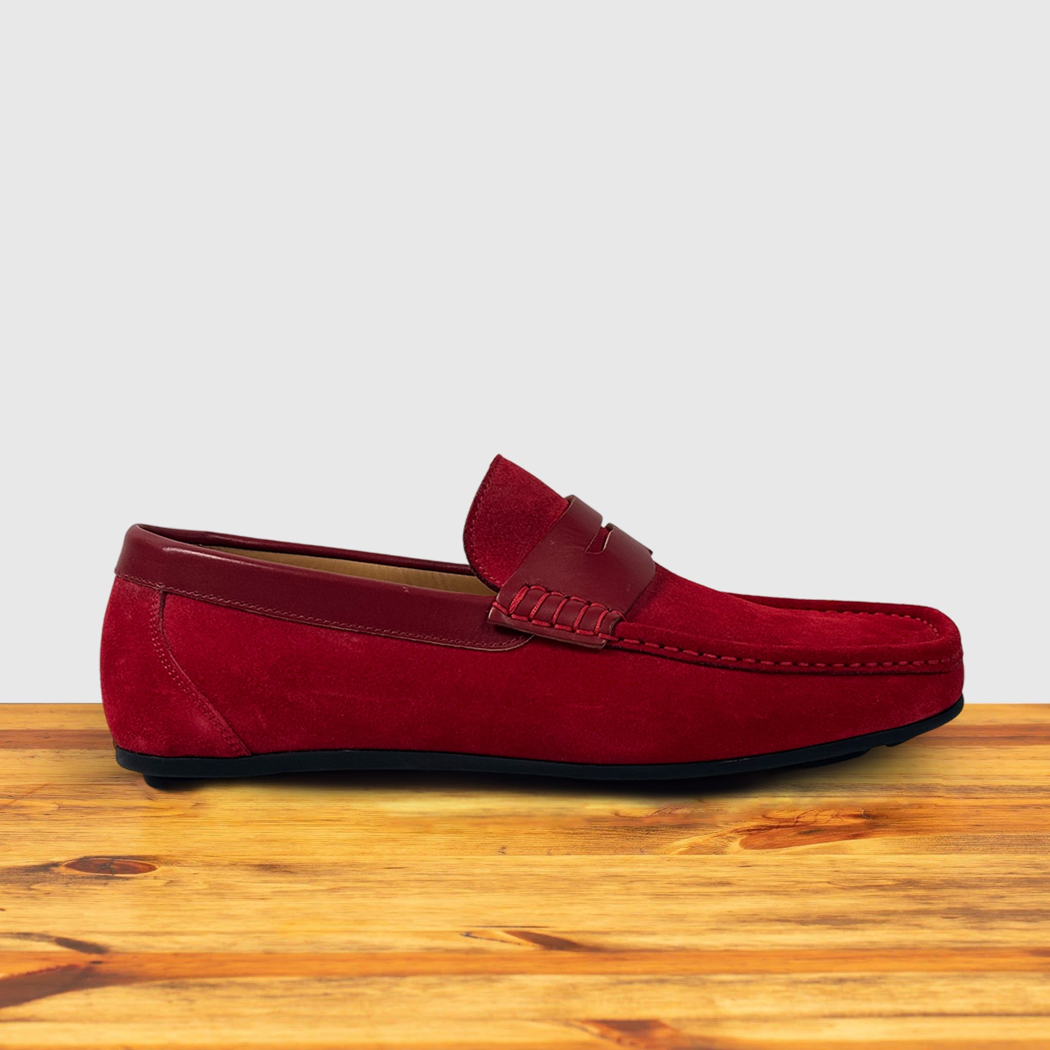 Red loafer shoe on a wooden surface with a light gray background
