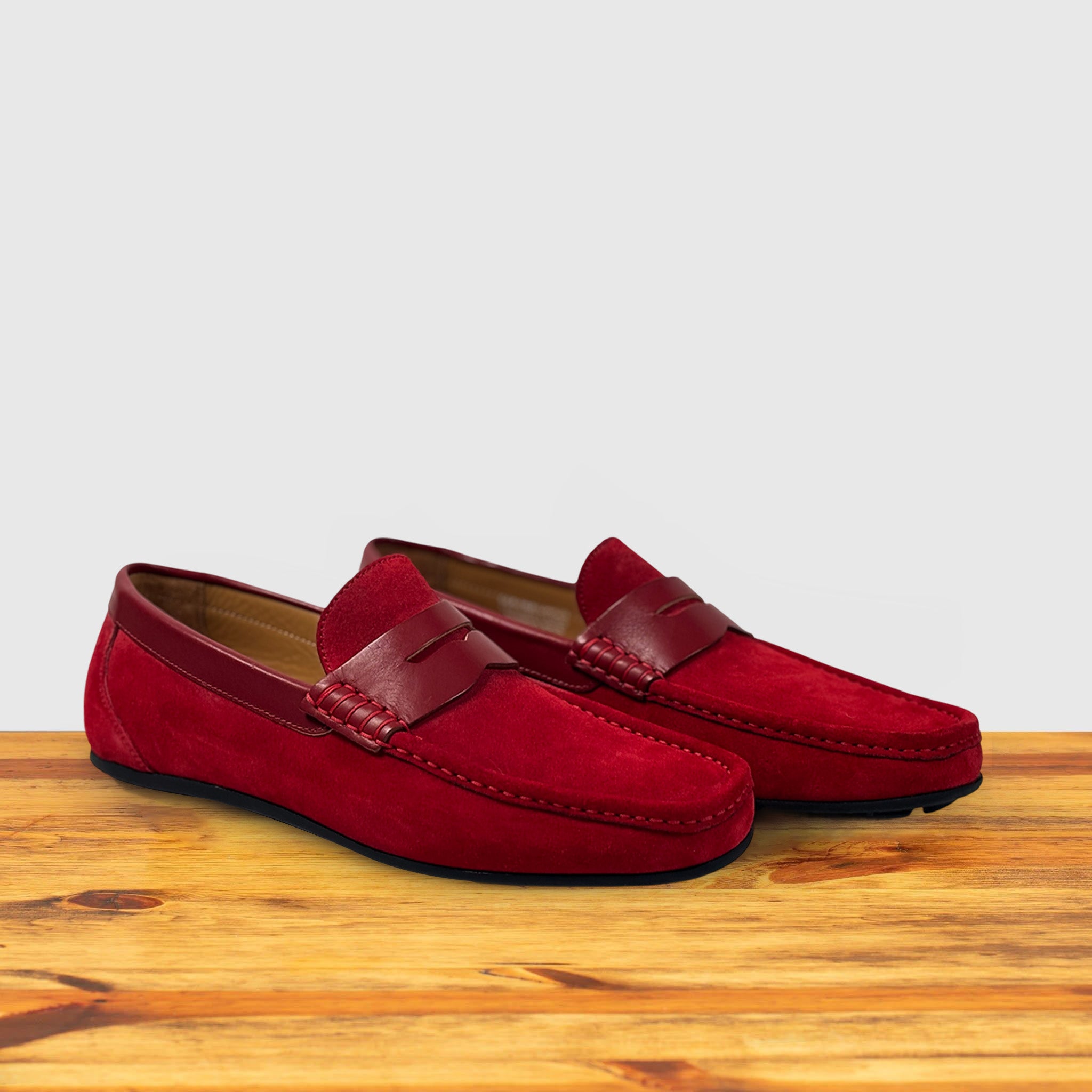 Pair of Red loafer shoe on a wooden surface with a light gray background