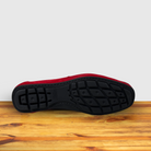 Outsole of Red loafer shoe on a wooden surface with a light gray background