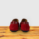 Red loafer shoe on a wooden surface with a light gray background