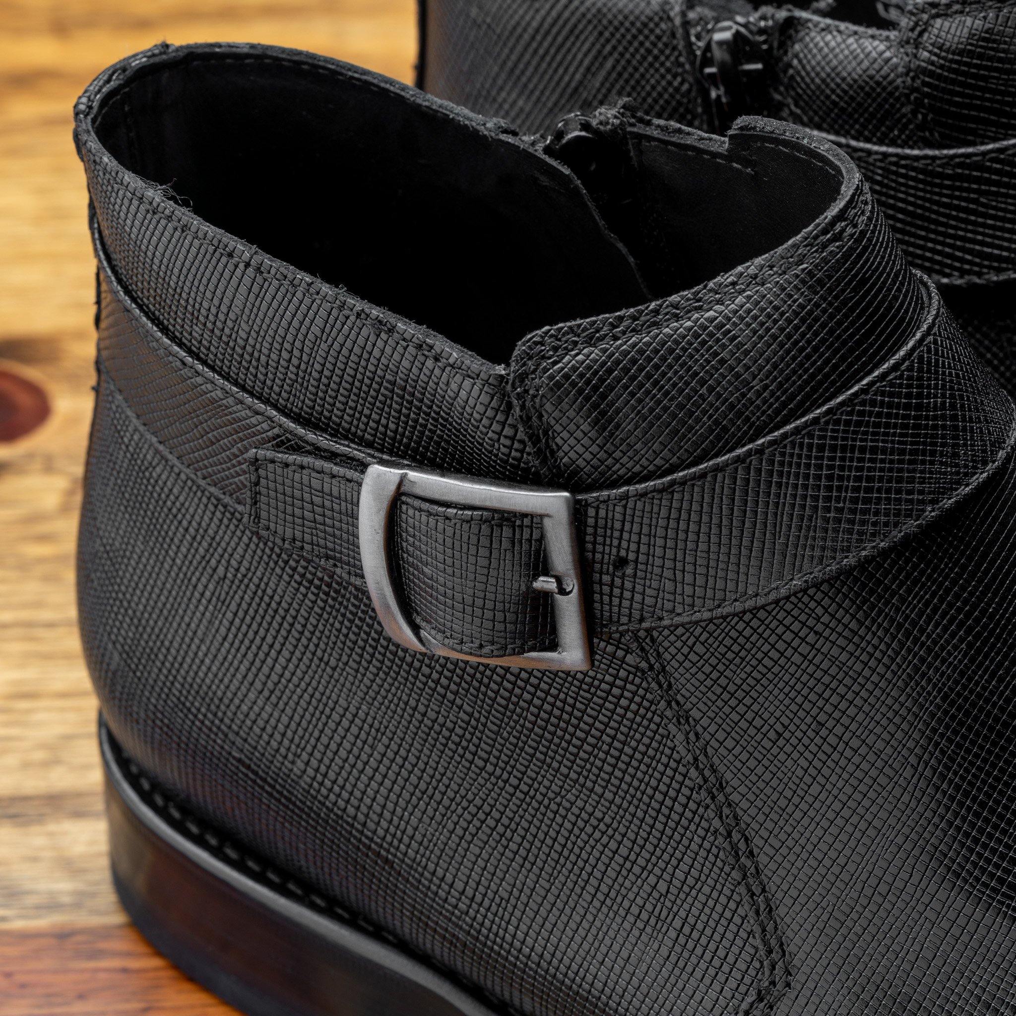 Close-up of Black leather boots on a wooden surface with a gray background