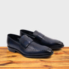 Blue leather loafer on a wooden surface with a light gray background