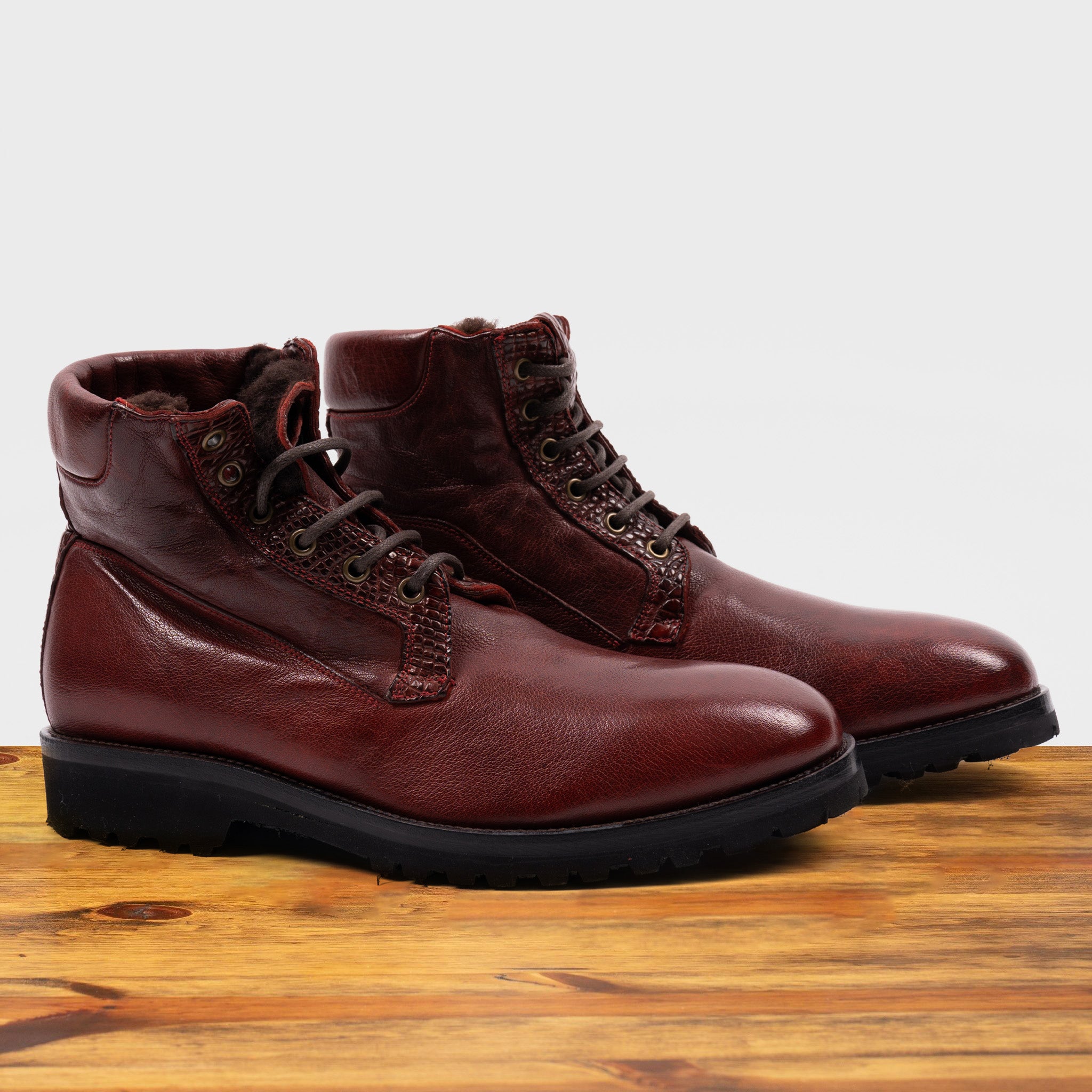 Pair of of Cherry leather boots on a wooden surface