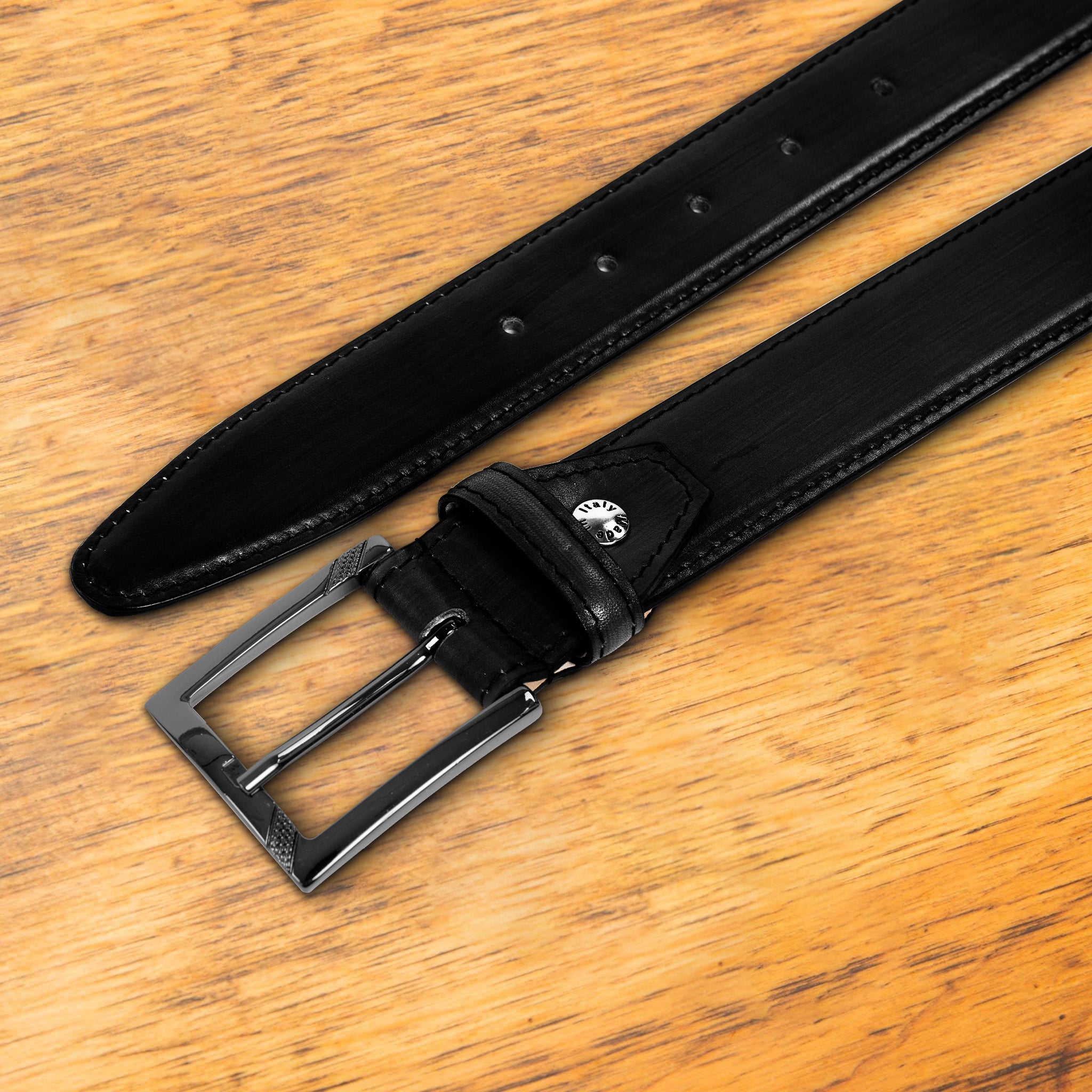 Black leather belt with a black buckle on a wooden surface
