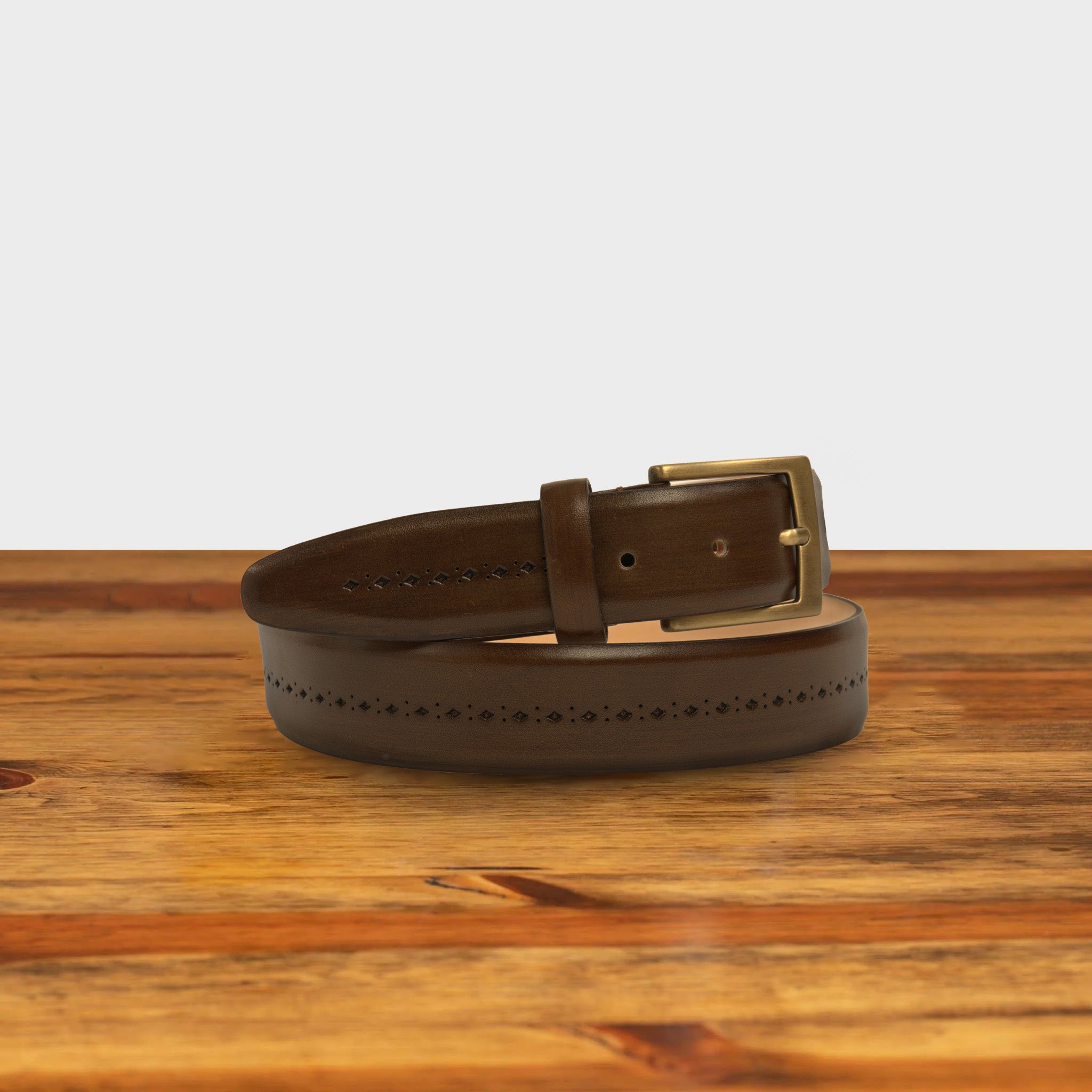 Brown leather belt with a gold buckle on a wooden surface