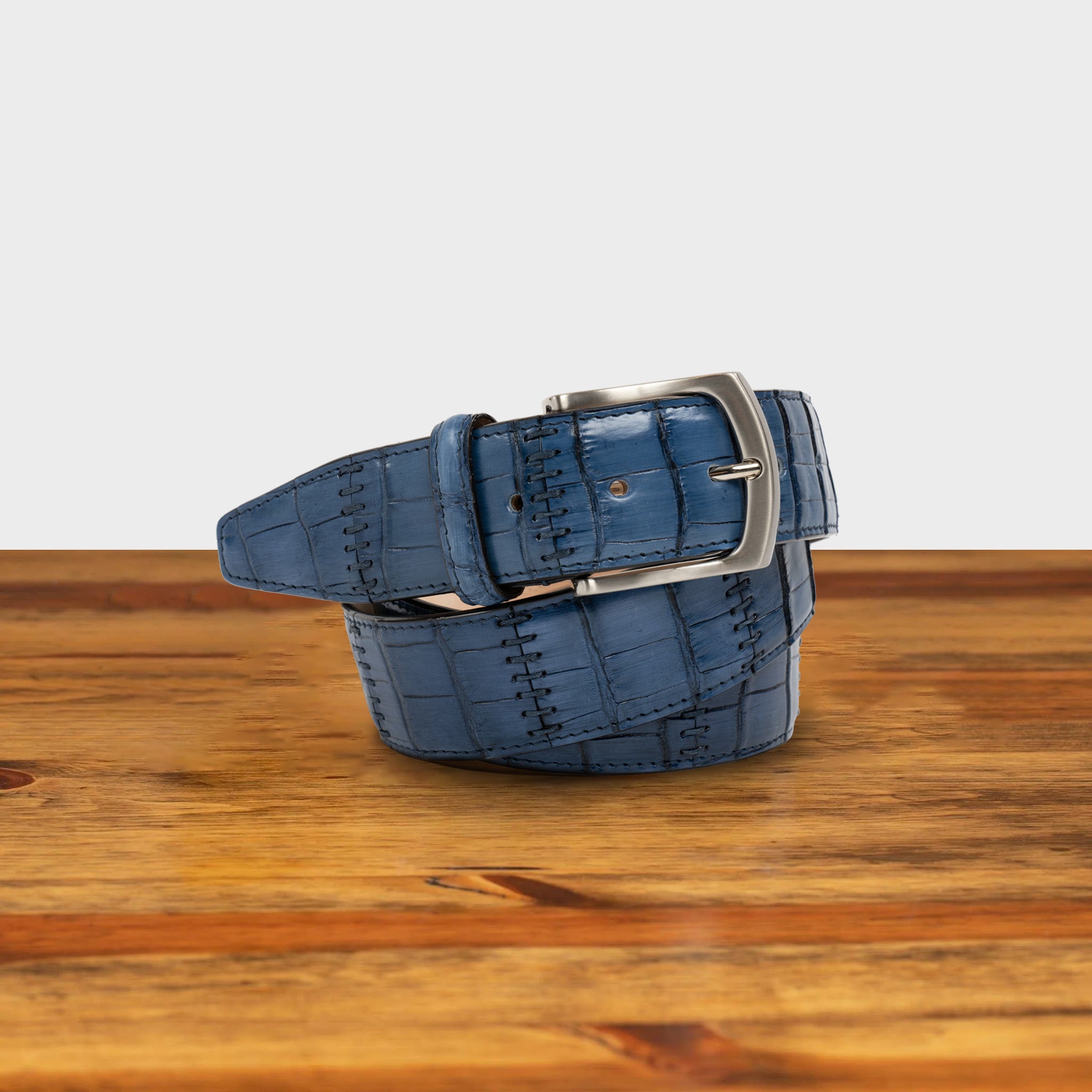 Blue textured belt with a silver buckle on a wooden surface