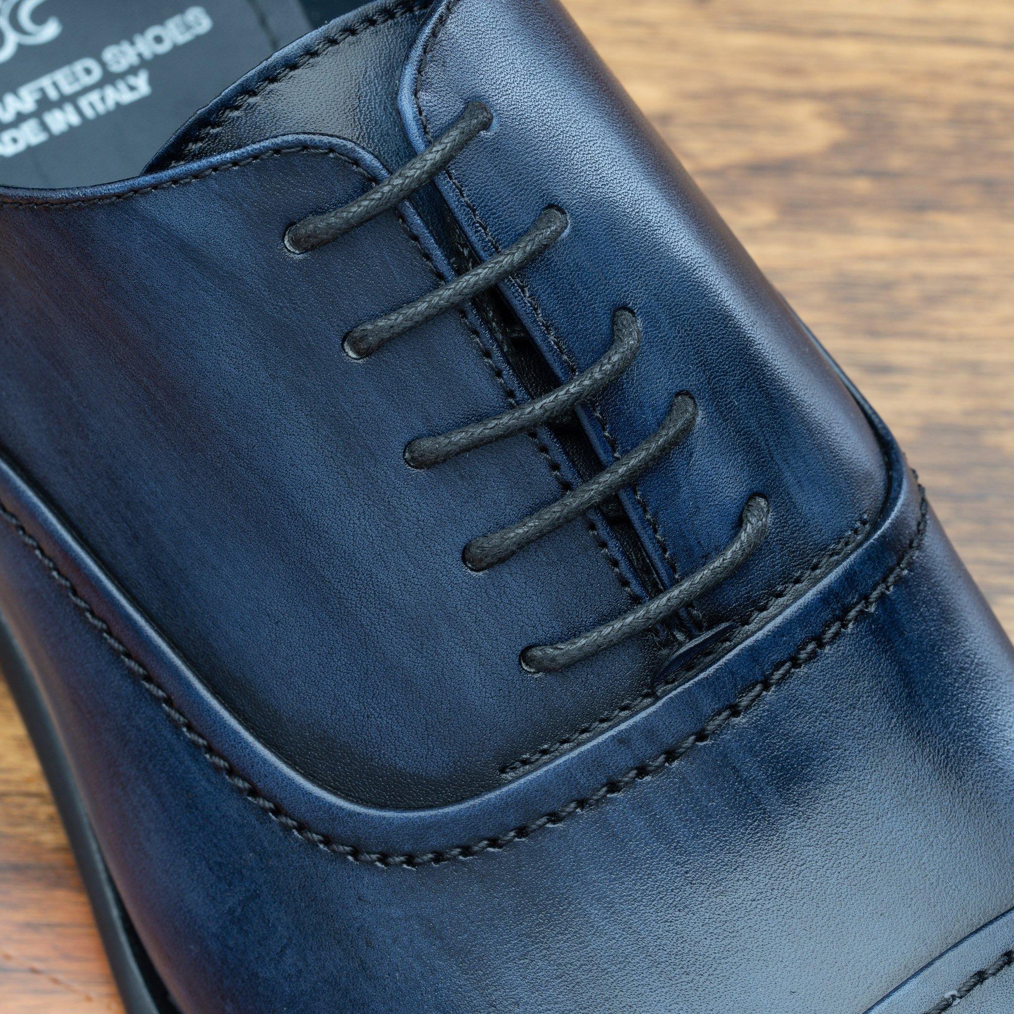 Close view of Blue leather dress shoe on a wooden surface