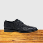 Blue ostrich dress shoe with studded details on a wooden surface