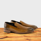 A Pair of Spice leather loafer on a wooden surface with a light gray background
