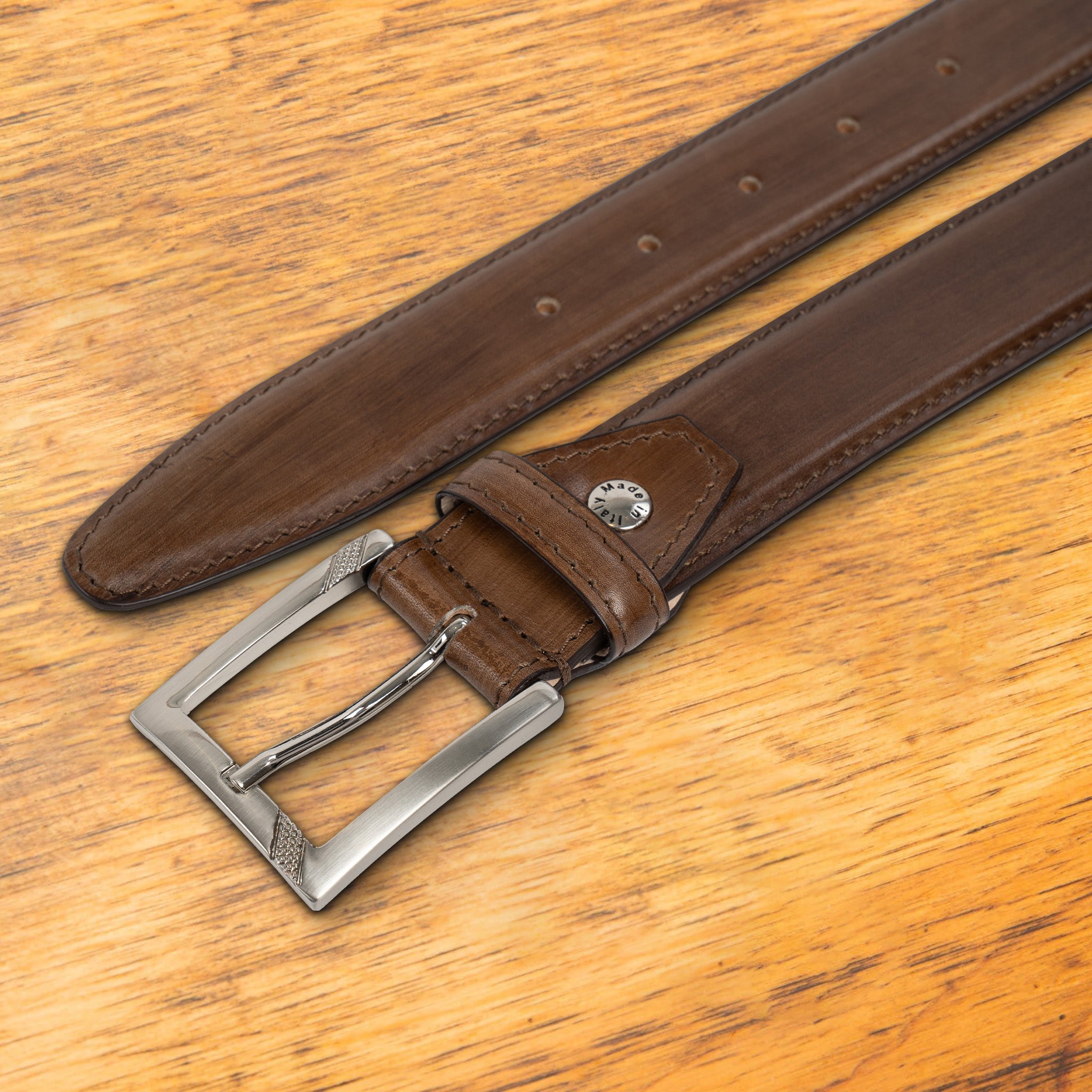 Brown leather belt with a black buckle on a wooden surface