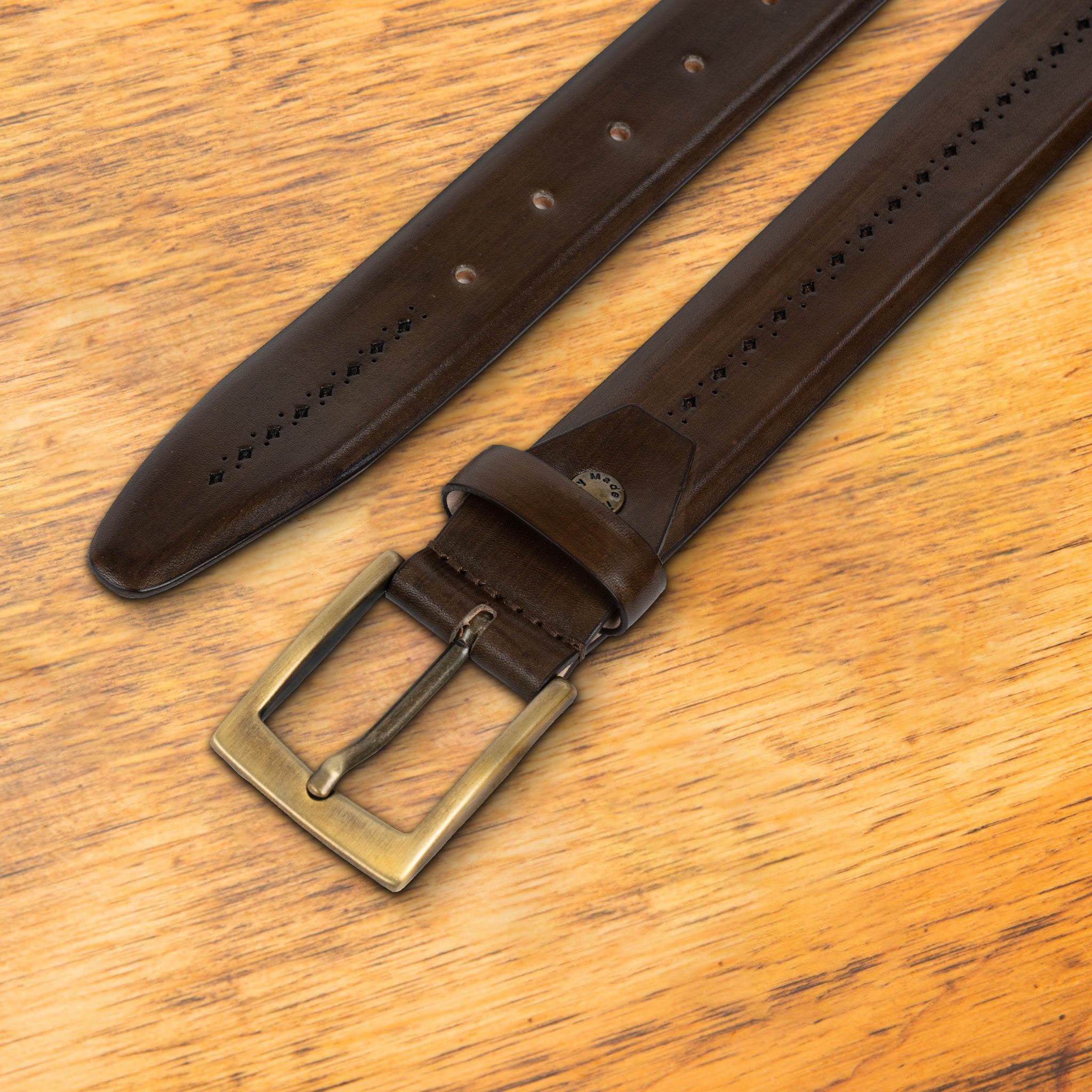Brown leather belt with a gold buckle on a wooden surface
