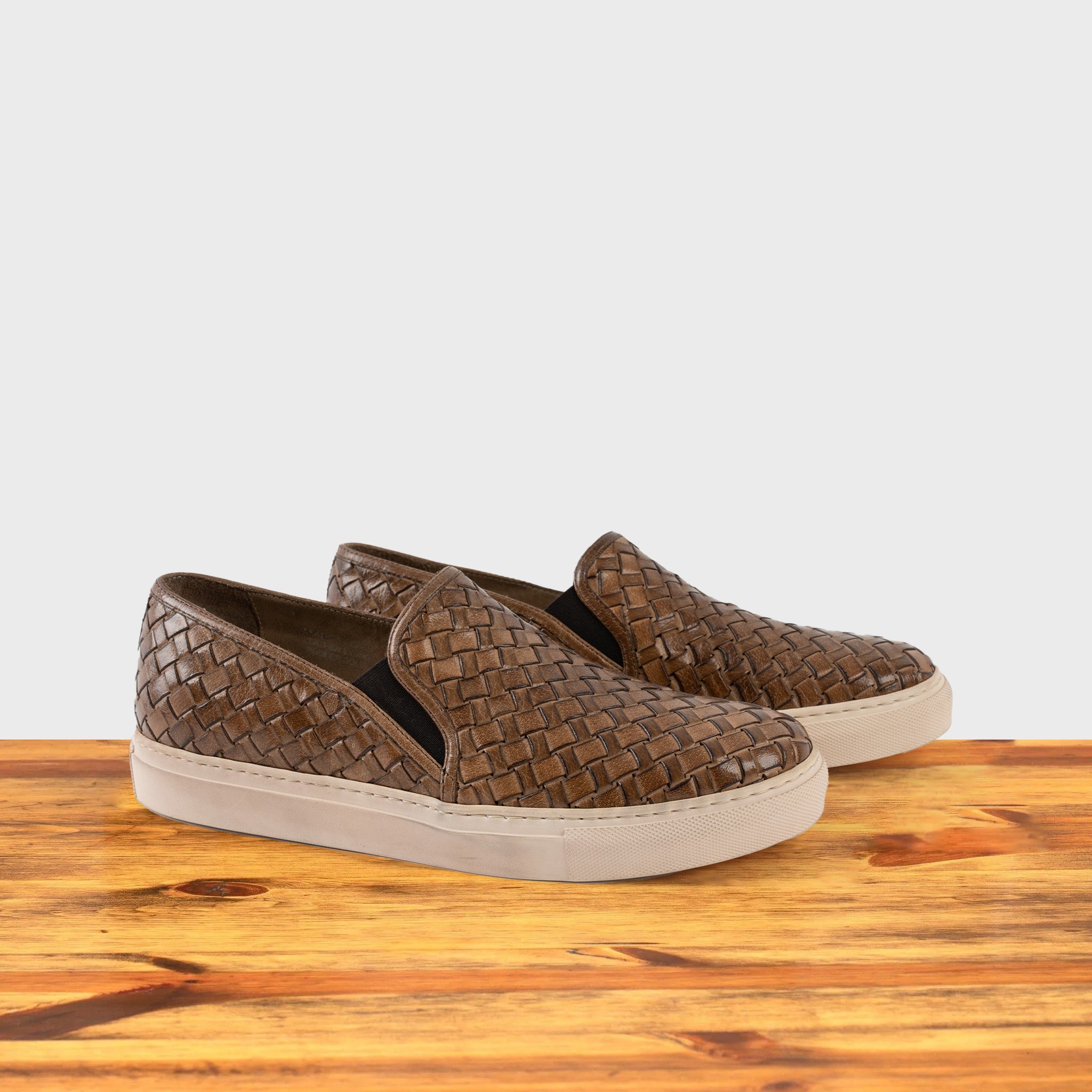 A Pair of Moor woven slip-on shoe on a wooden surface with a white background
