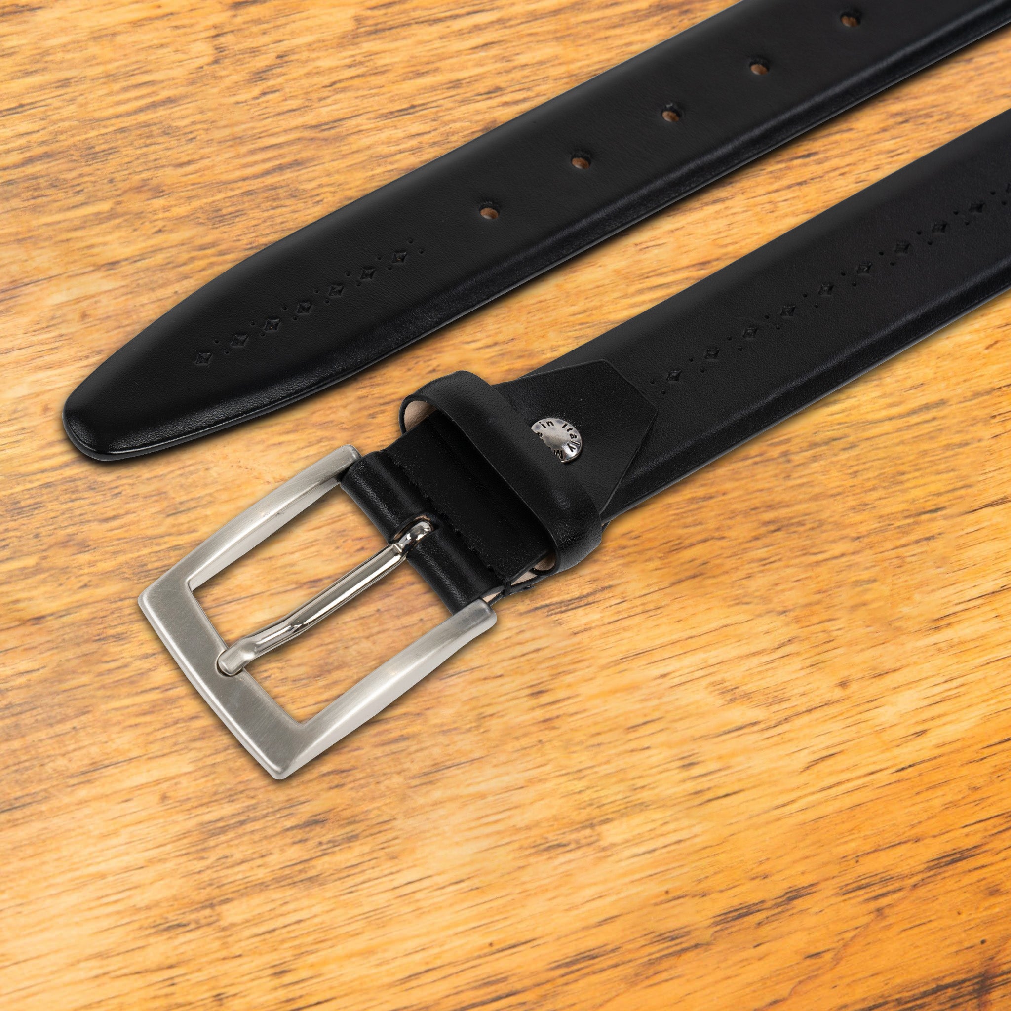 Black leather belt with a gold buckle on a wooden surface