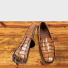 A Pair of Brick crocodile-patterned loafer on a wooden surface with a light gray background