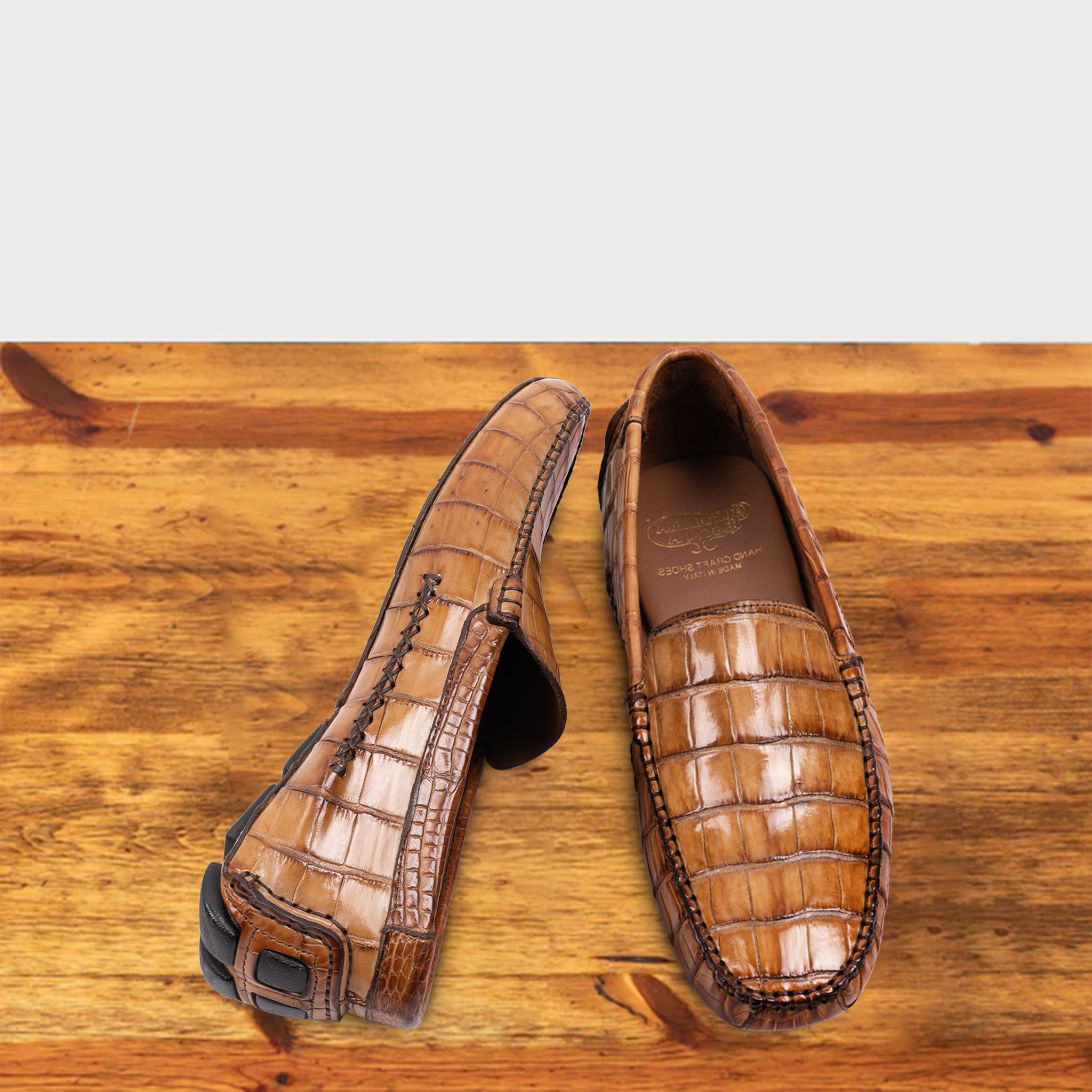 A Pair of Brick crocodile-patterned loafer on a wooden surface with a light gray background