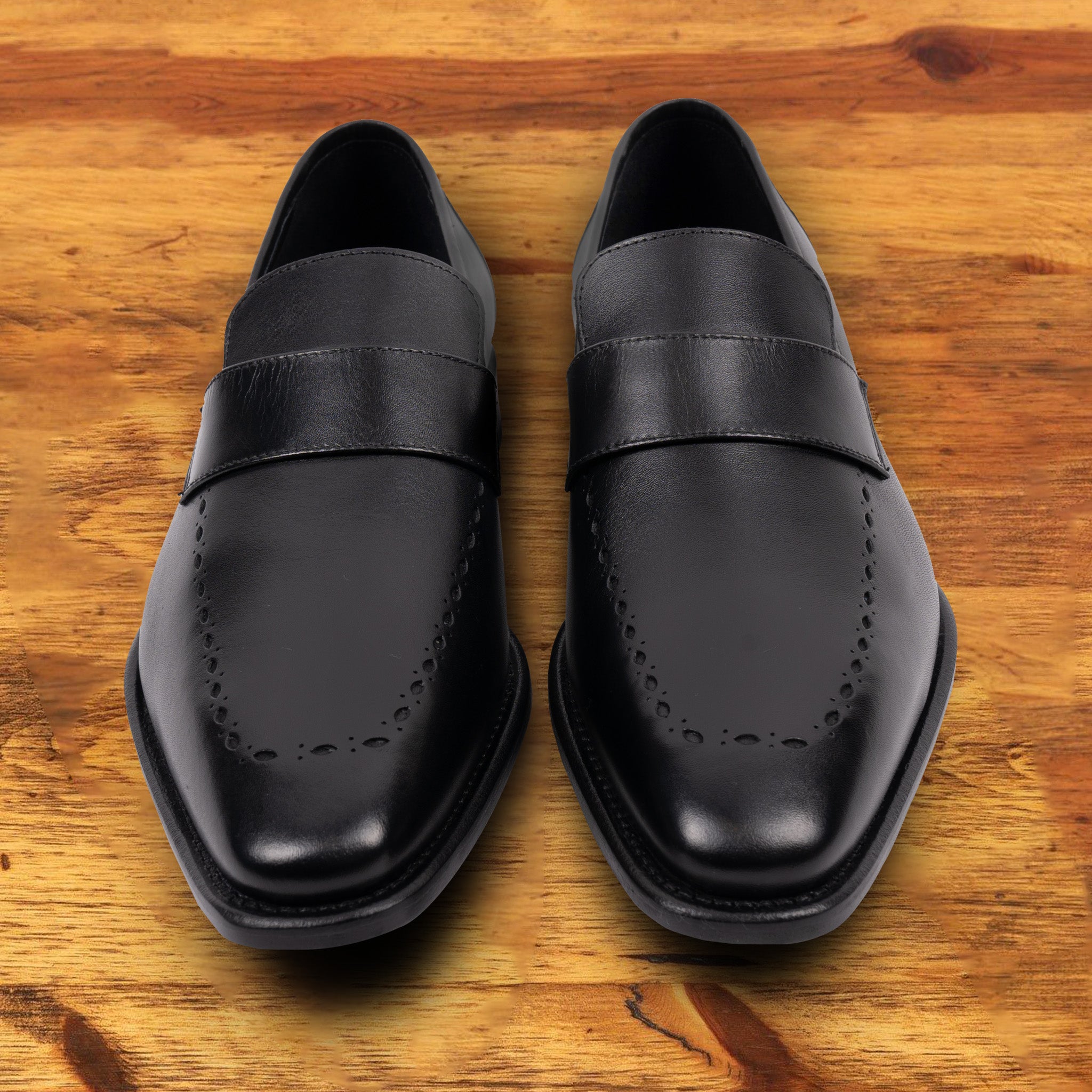 A Pair of Black leather loafer on a wooden surface 