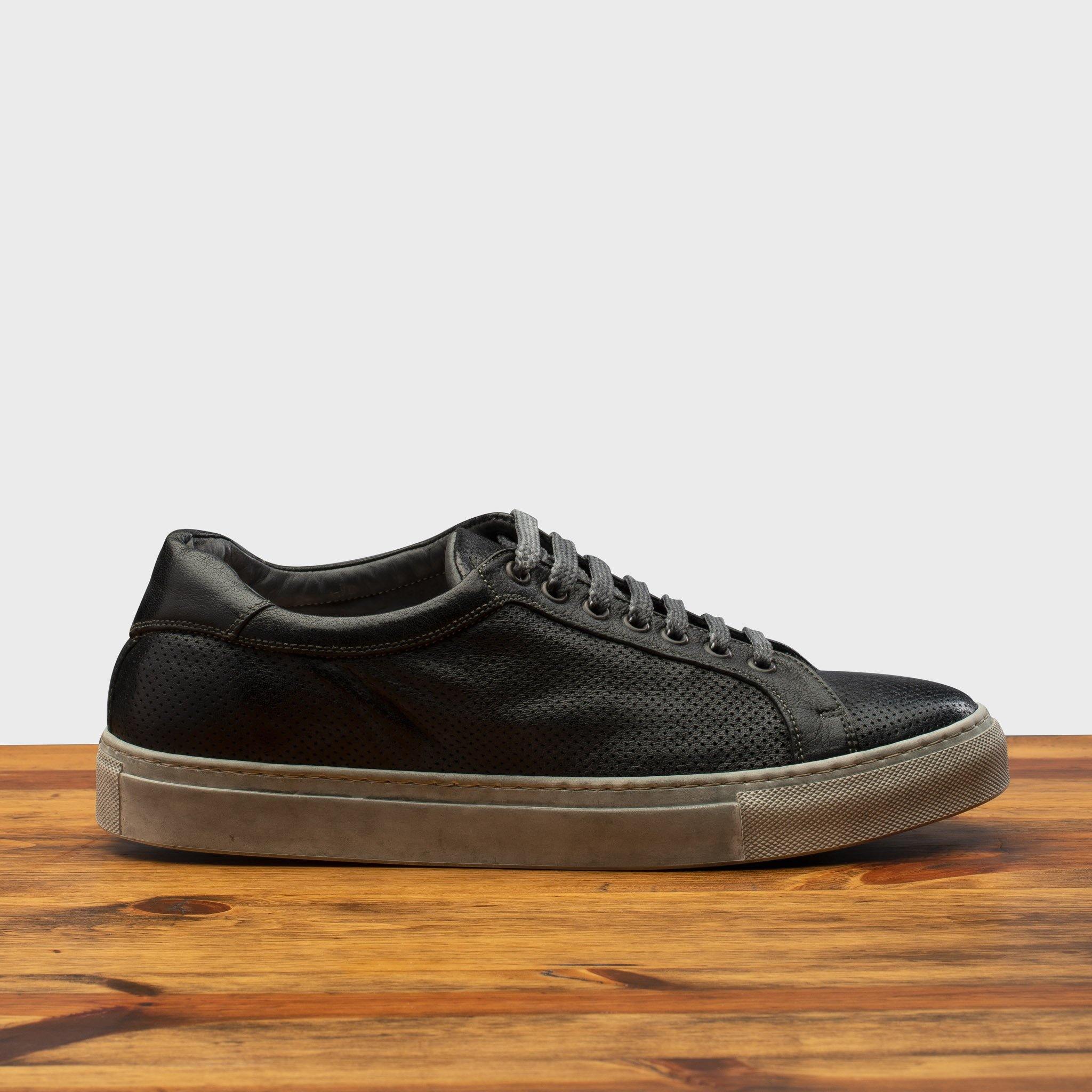 Black sneaker on a wooden surface with a gray background