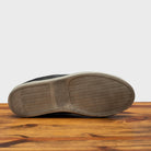 Outsole of Black sneaker on a wooden surface with a gray background