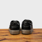 Back view of Black sneaker on a wooden surface with a gray background