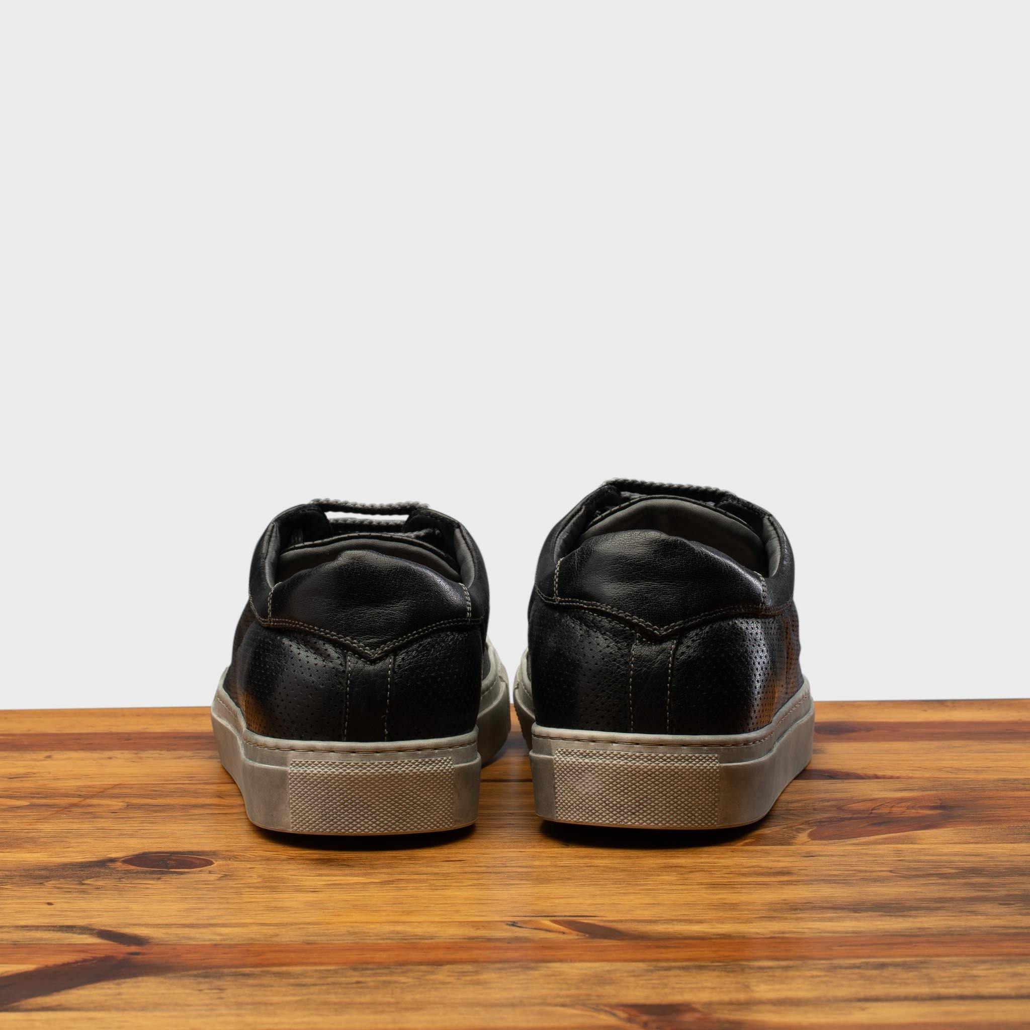 Back view of Black sneaker on a wooden surface with a gray background