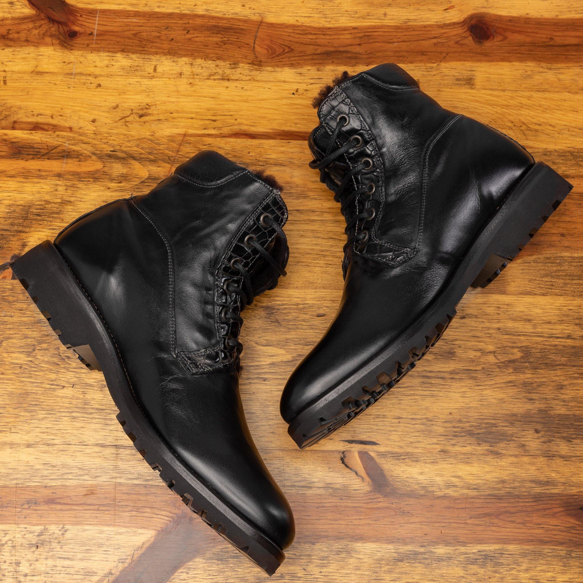  Pair of black leather boots on a wooden surface