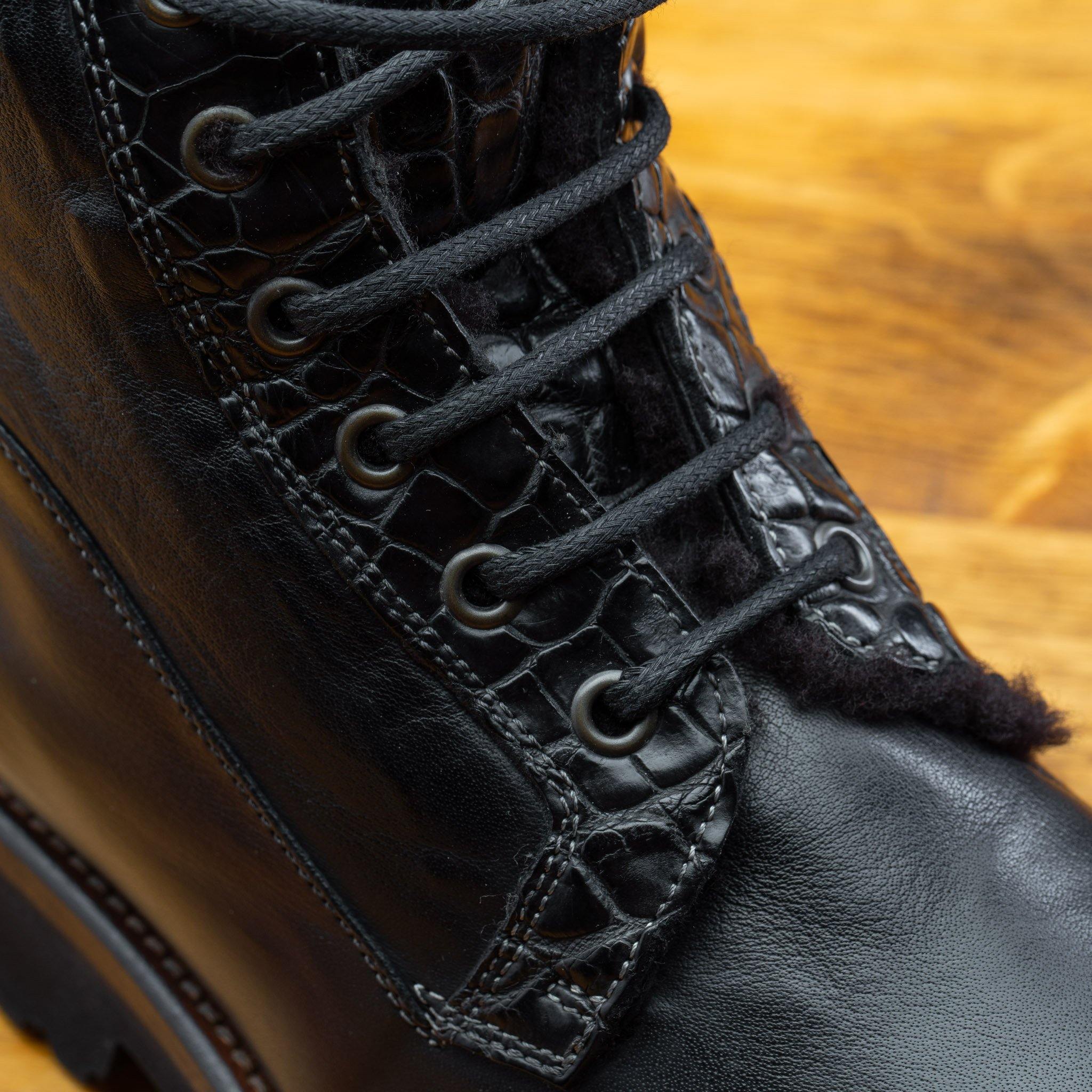 Close view of Black leather boots on a wooden surface