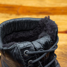 Close view of Black leather boots on a wooden surface